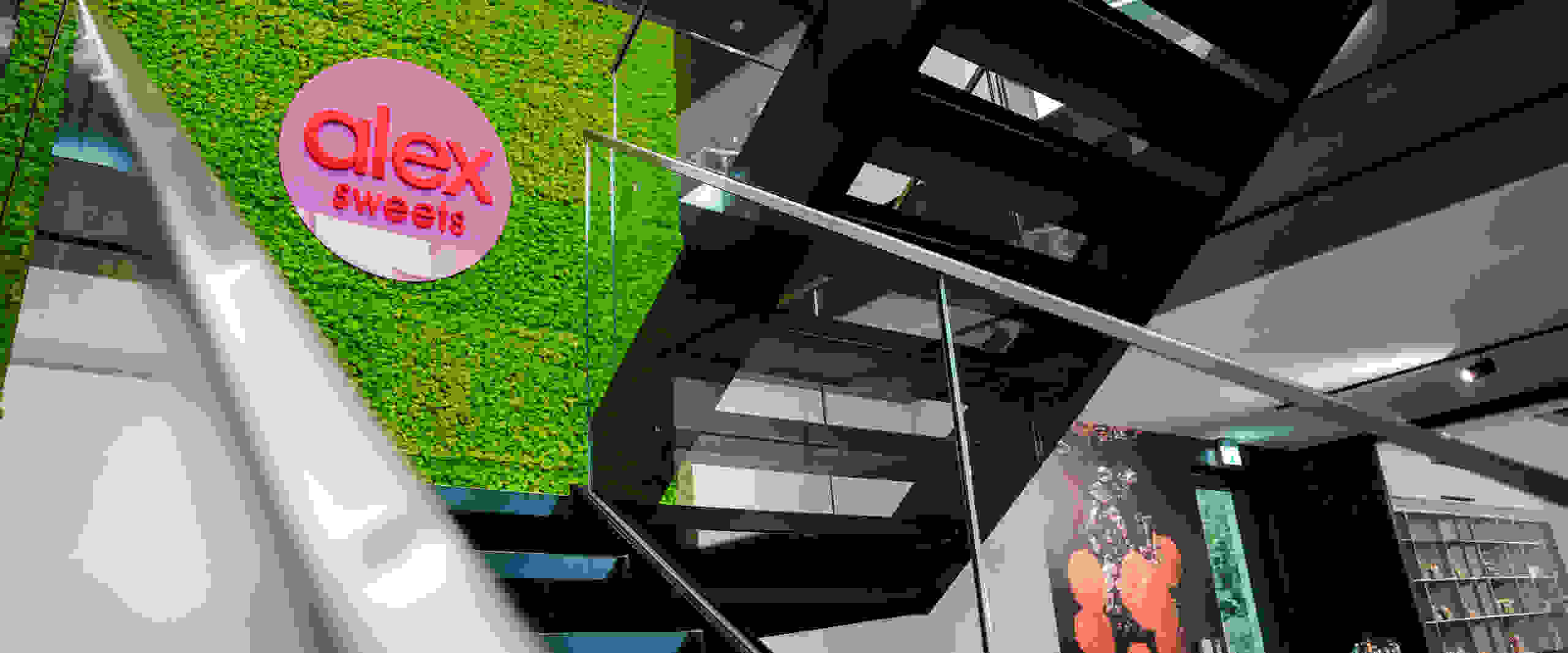 Modern staircase with glass banisters and a light green moss wall. The 