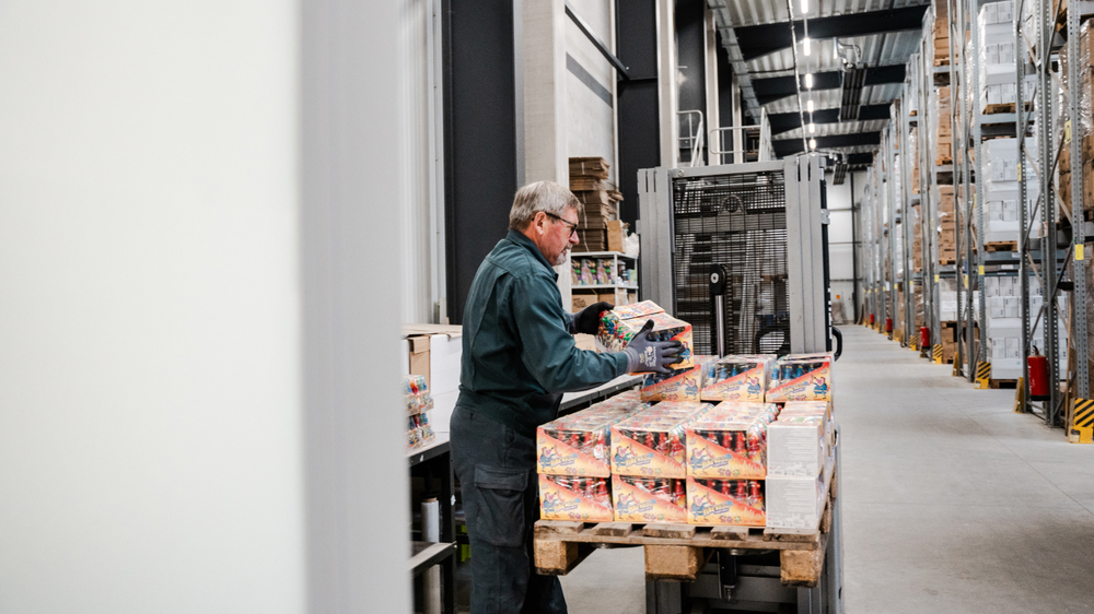 Un empleado de almacén apila productos en un palé.