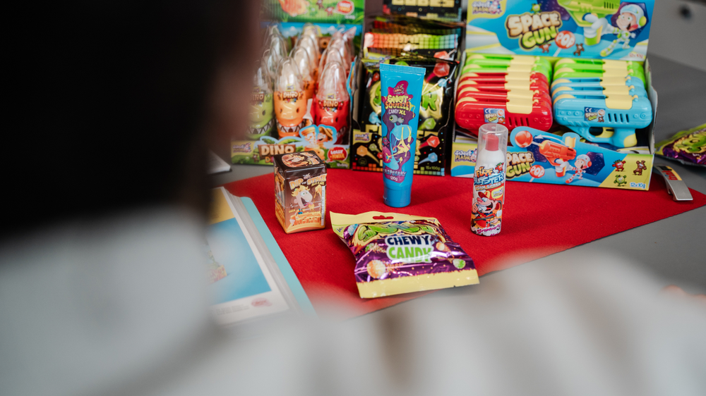 Un tavolo con dolci e giocattoli colorati, tra cui caramelle fantasma, caramelle gommose e pistole spaziali.